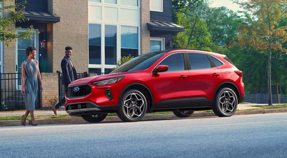 Two people walking up to a red 2025 Ford Escape from the side.