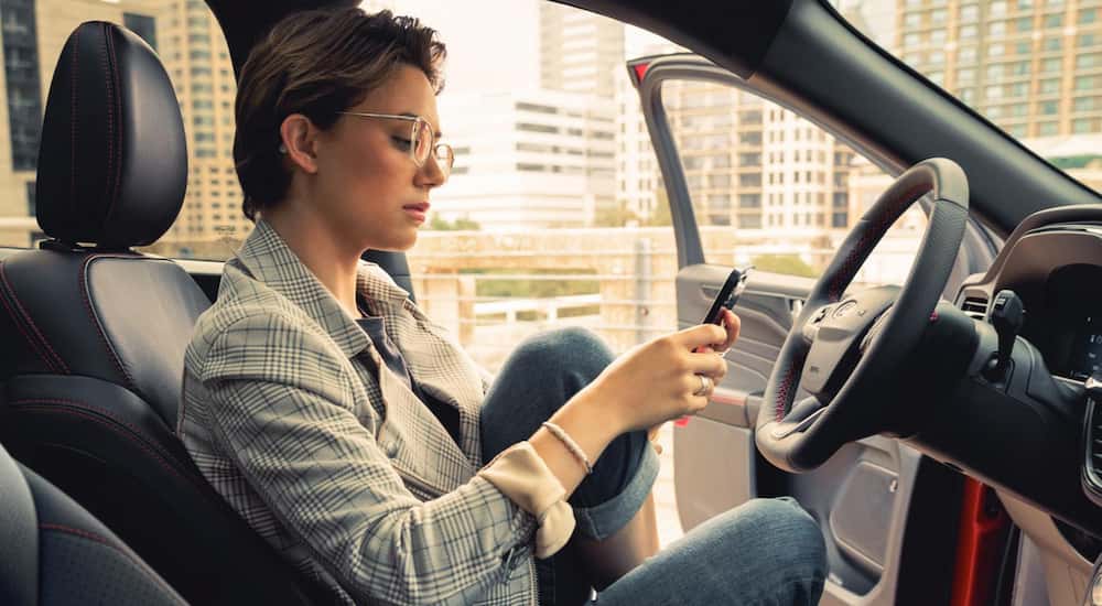 A person sits inside a2025 Ford Escape to compare it vs. a 2025 Nissan Rogue.