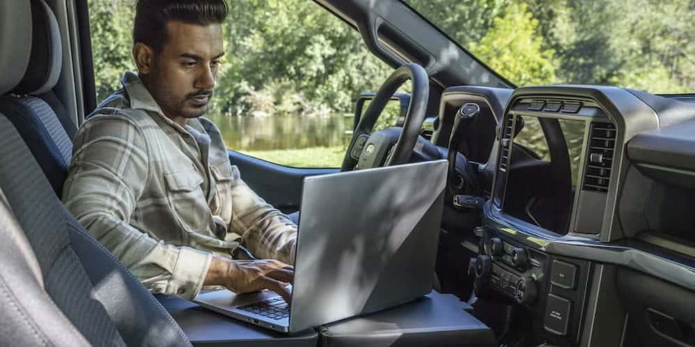 A person uses their laptop on the center console of their 2025 F-150.