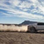 White 2025 Ford F-150 Raptor driving off-road.