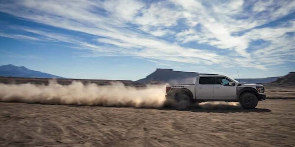 White 2025 Ford F-150 Raptor driving off-road.