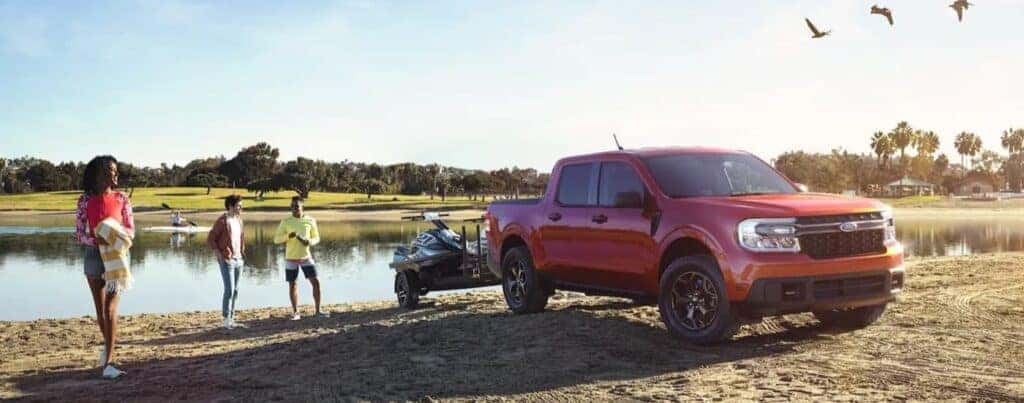 A red 2023 Ford Maverick towing a boat.