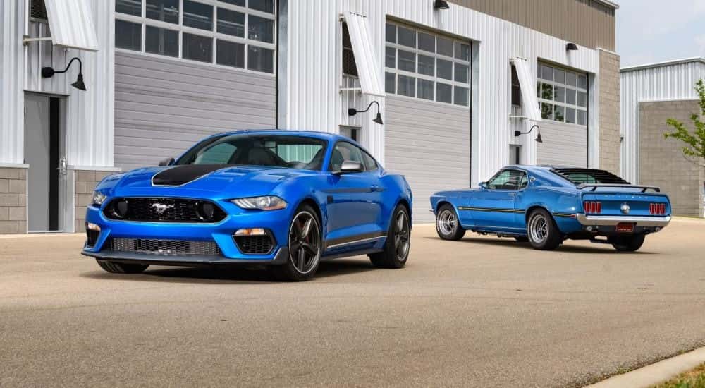 Two blue Ford Mustang Mach 1 2021 and 1969 parked in a parking lot.