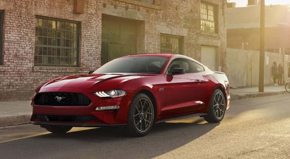 Red 2022 Ford Mustang parked at an angle in front of a brick building.