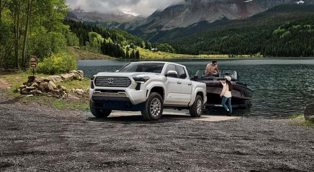 White 2026 Toyota Tacoma towing boat out of a lake.