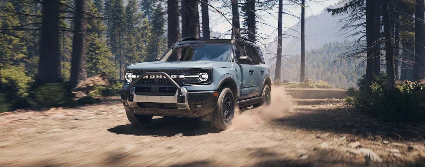 A blue 2025 Ford Bronco off-roading on a trail