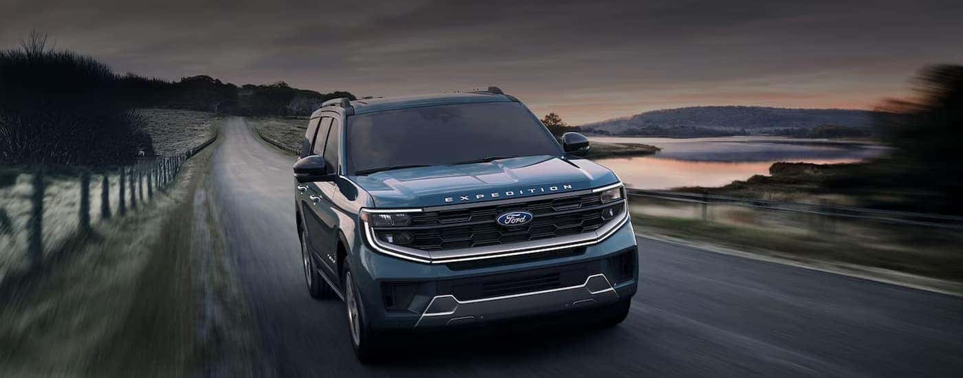A blue 2025 Ford Expedition driving down a rural road