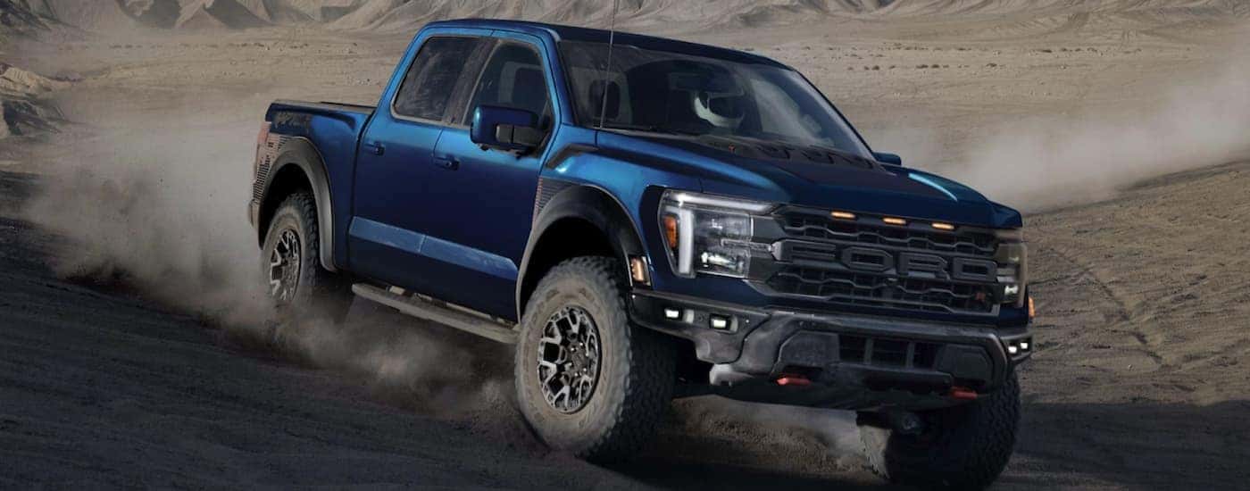A blue 2025 Ford F-150 Raptor off-roading in dirt