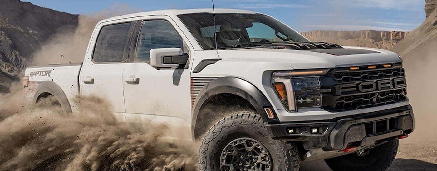 A white 2025 Ford F-150 Raptor off-roading in sand