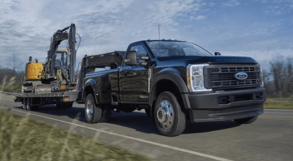 Black 2026 Ford F-450 towing an excavator down a road