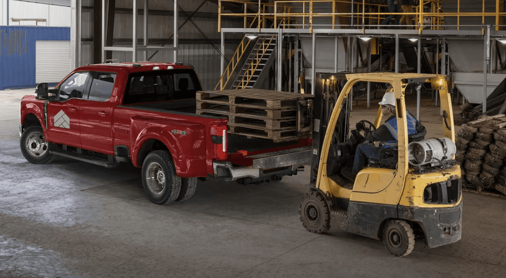 A forklift loads pallets into the bed of a red 2026 Ford F-450