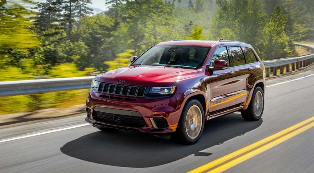 Red 2018 Jeep Grand Cherokee driving to a used car dealer near Colonie