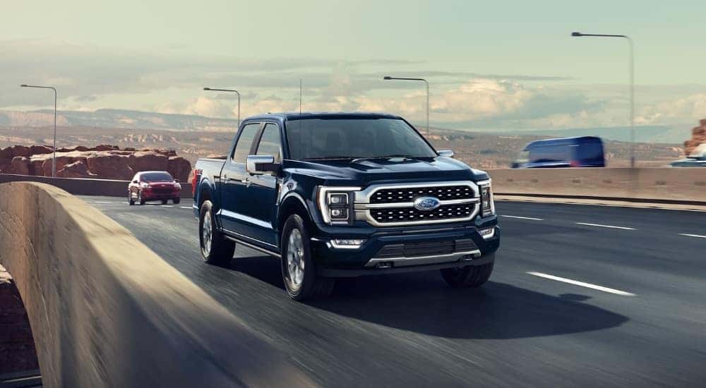 Blue 2023 Ford F-150 driving to a used car dealer near Latham