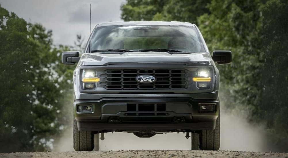 A gray 2025 Ford F-150 Lariat driving on a dirt road.