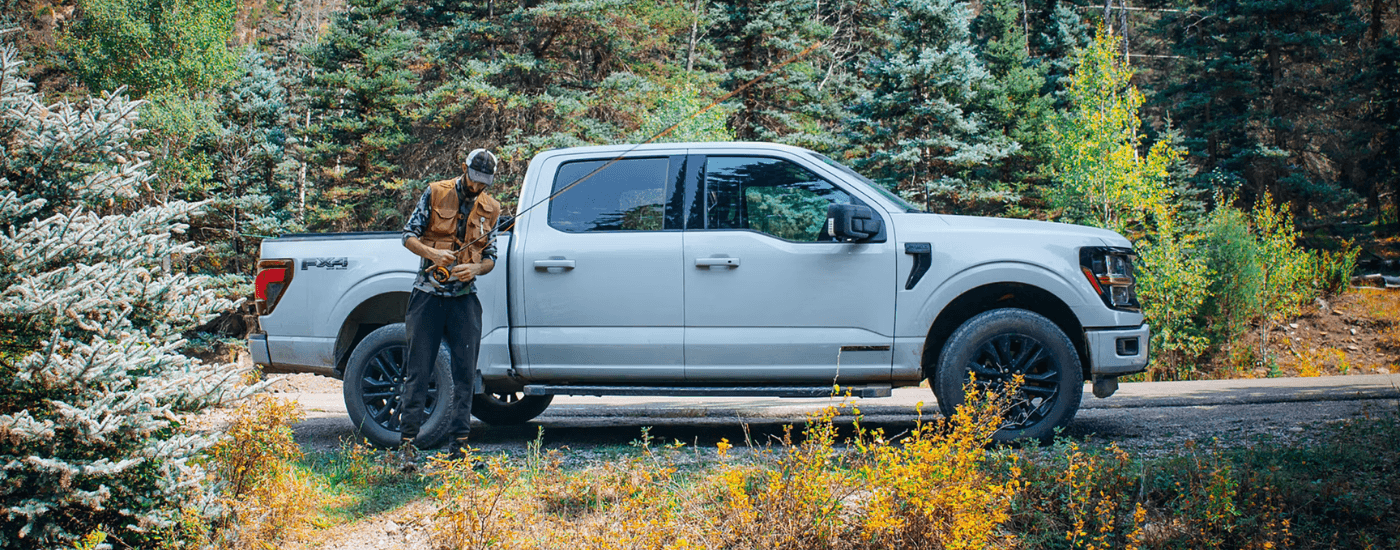 A person sets up a fishing rod next to their silver 2025 Ford F-150 Lariat