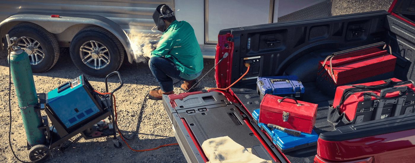A person using the Pro Power Onboard on their red 2025 Ford F-150 Lariat