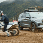 A dirt bike kicking up dirt next to a silver 2026 Ford Explorer Tremor