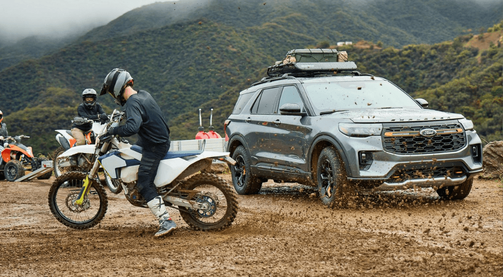 A dirt bike kicking up dirt next to a silver 2026 Ford Explorer Tremor