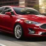 Red 2020 Ford Fusion driving on a city street