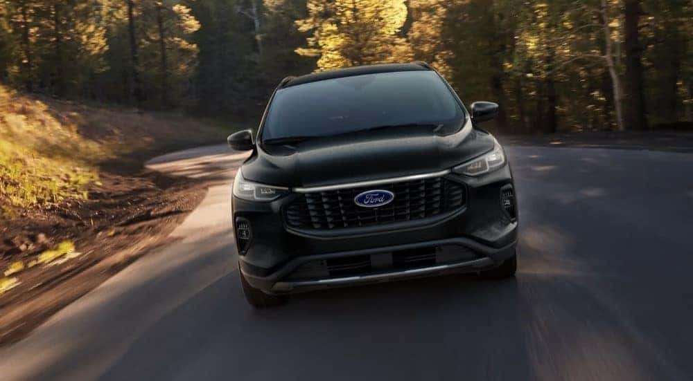 A black 2024 Ford Escape driving down a road
