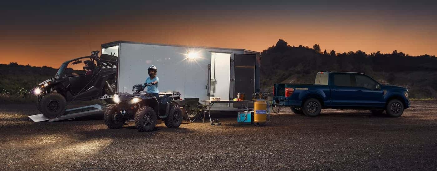 Blue 2026 Ford F-150 towing a trailer for ATVs