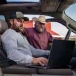 Two people using a laptop in a 2026 Ford F-150.
