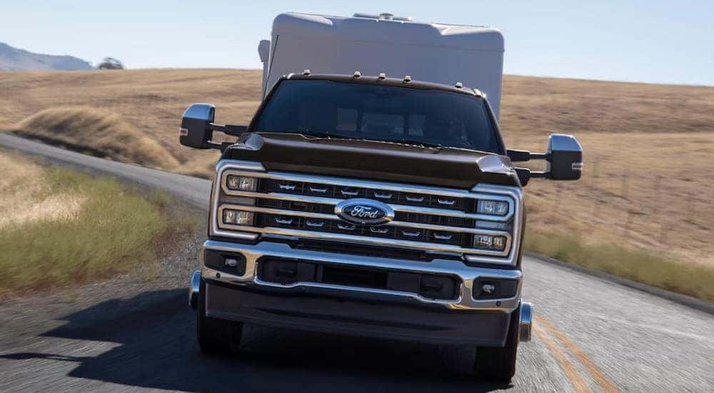 Front of a black 2026 Ford F-350 Lariat towing a camper van.