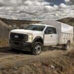 A white 2026 Ford F-450 driving on a dirt road.