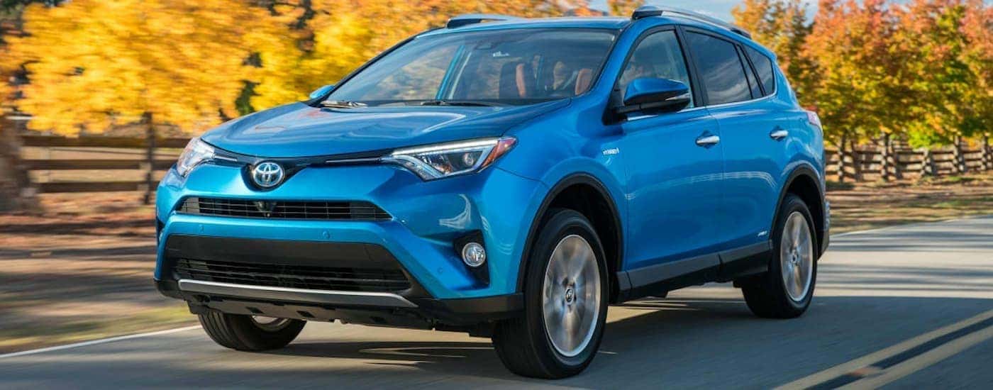 Blue 2016 Toyota RAV4 driving down a road.