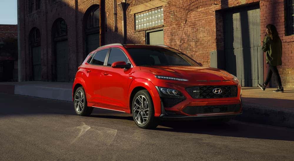 Red 2022 Hyundai Kona parked by a building.
