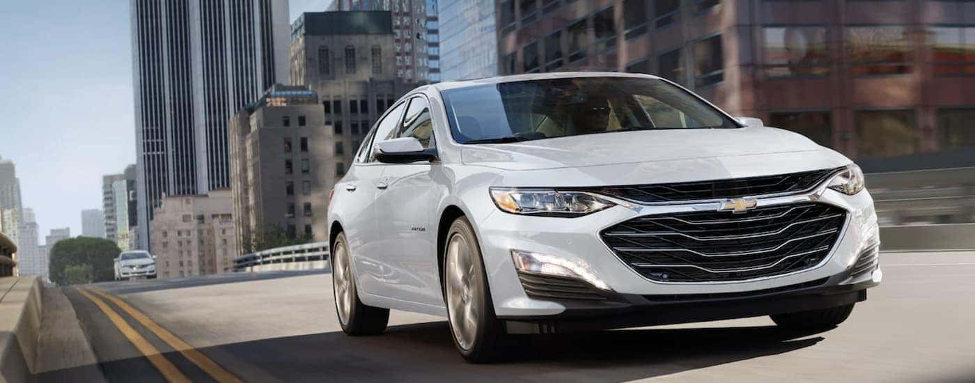 A white 2022 Chevy Malibu driving in a city