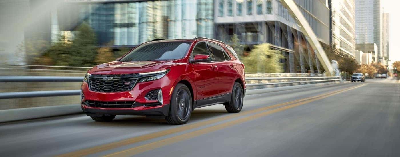 A red used 2024 Chevy Equinox RS driving from a car dealer near Amsterdam
