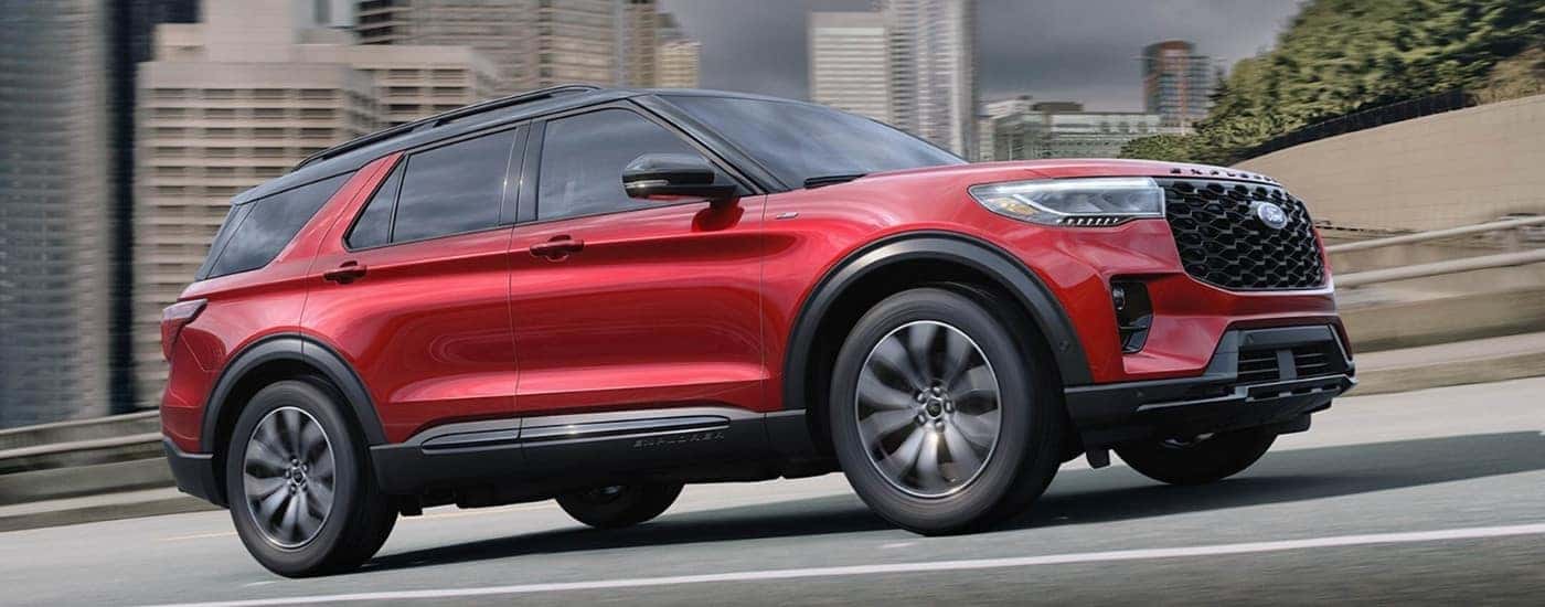 A red 2025 Ford Explorer ST-Line driving from a dealership near Pittsfield