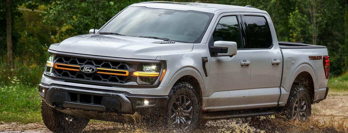 A gray 2026 Ford F-150 off-roading in mud