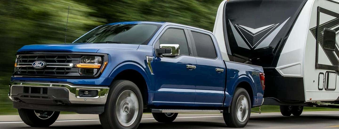 A blue 2026 Ford F-150 towing a camper