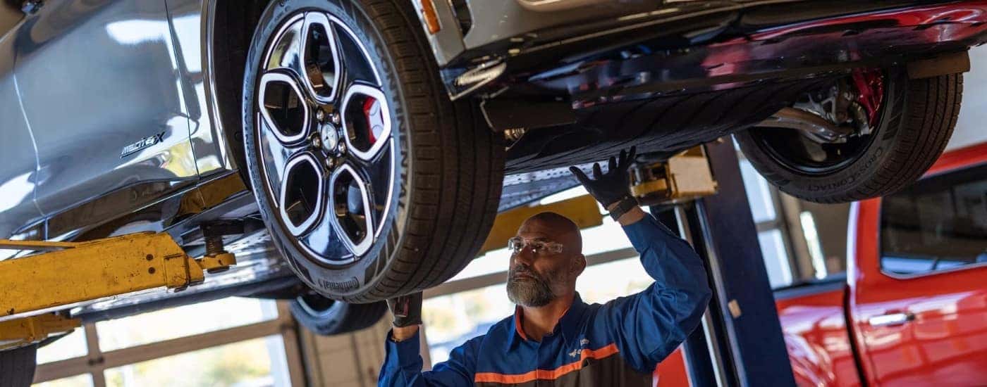 A technician checking the undercarriage on a 2024 Ford Mustang Mach-E