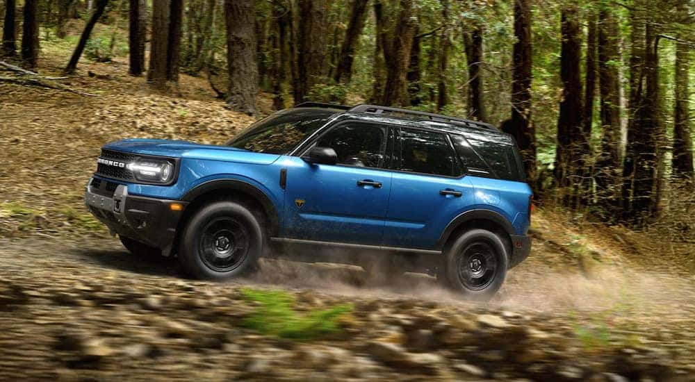 Blue 2026 Ford Bronco Sport driving off-road through a forest.
