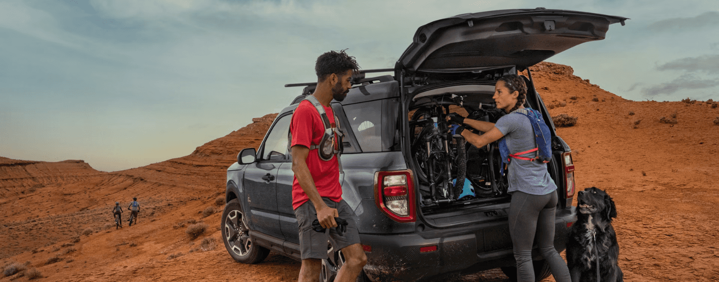A couple unloading bikes from the trunk of their black 2026 Ford Bronco Sport