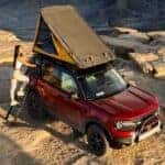 A person setting up the roof top tent on their red 2026 Ford Bronco Sport