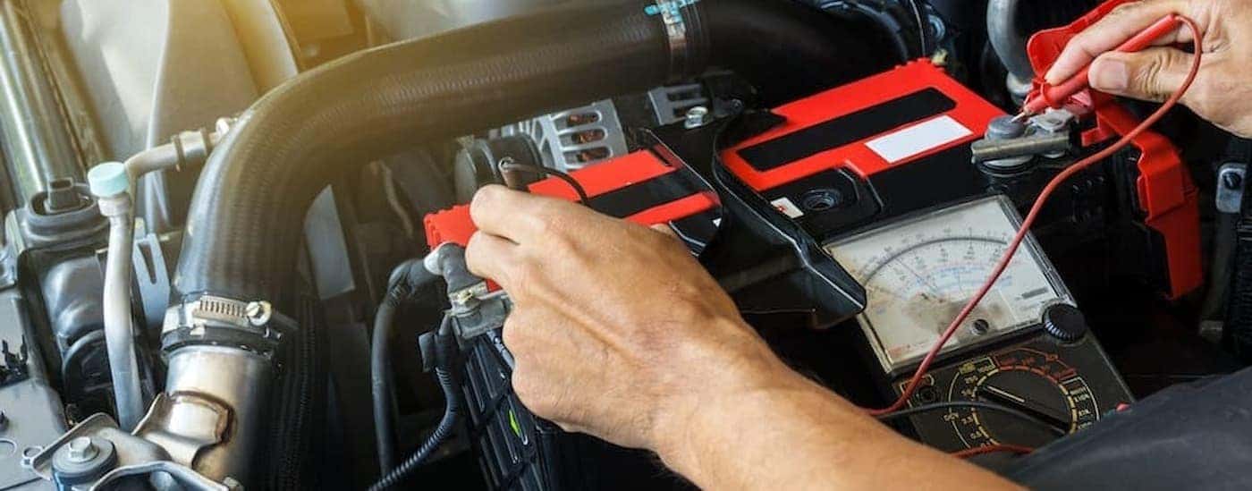 A technician using a multimeter on a battery.