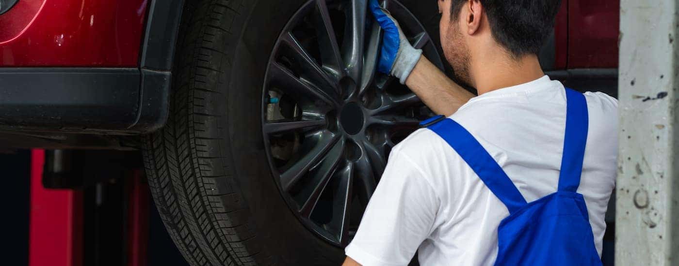Mechanic putting a tire on a red vehicle
