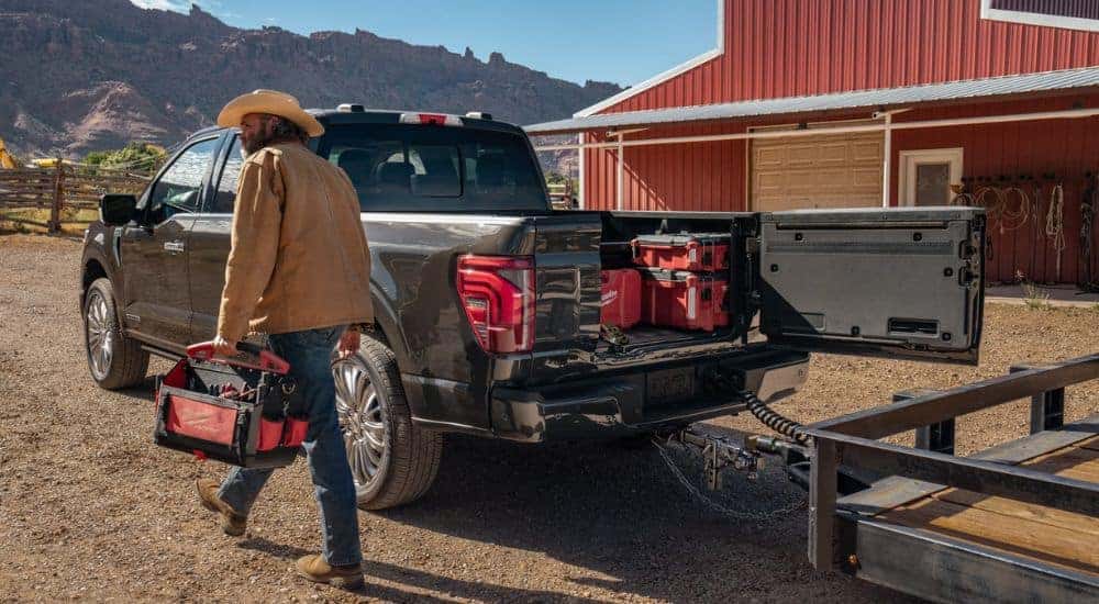 Black 2026 Ford towing a trailer with tools in the bed