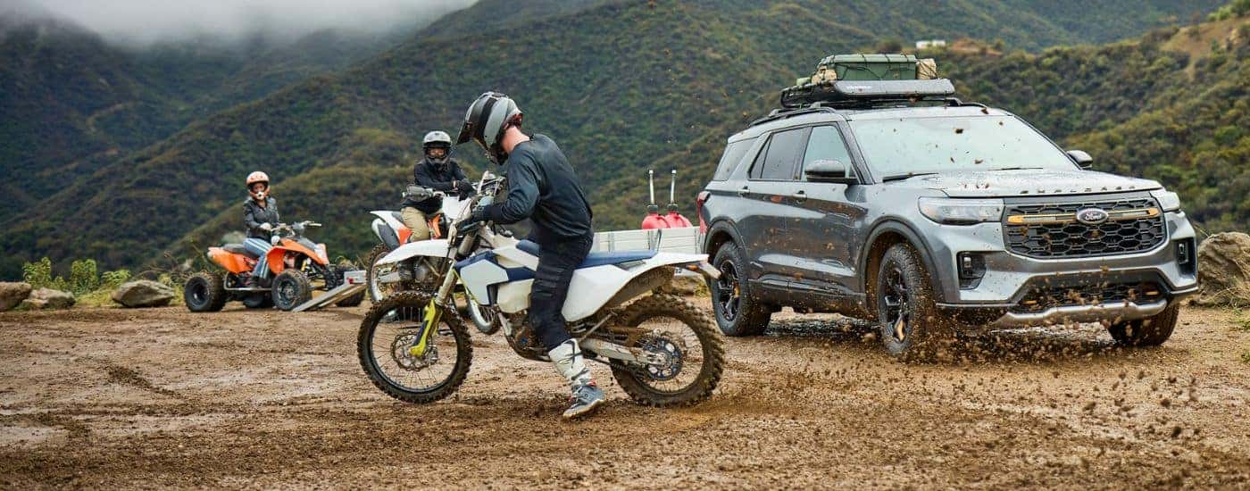 Grey 2026 Ford Explorer parked in mud and people on dirt bikes nearby