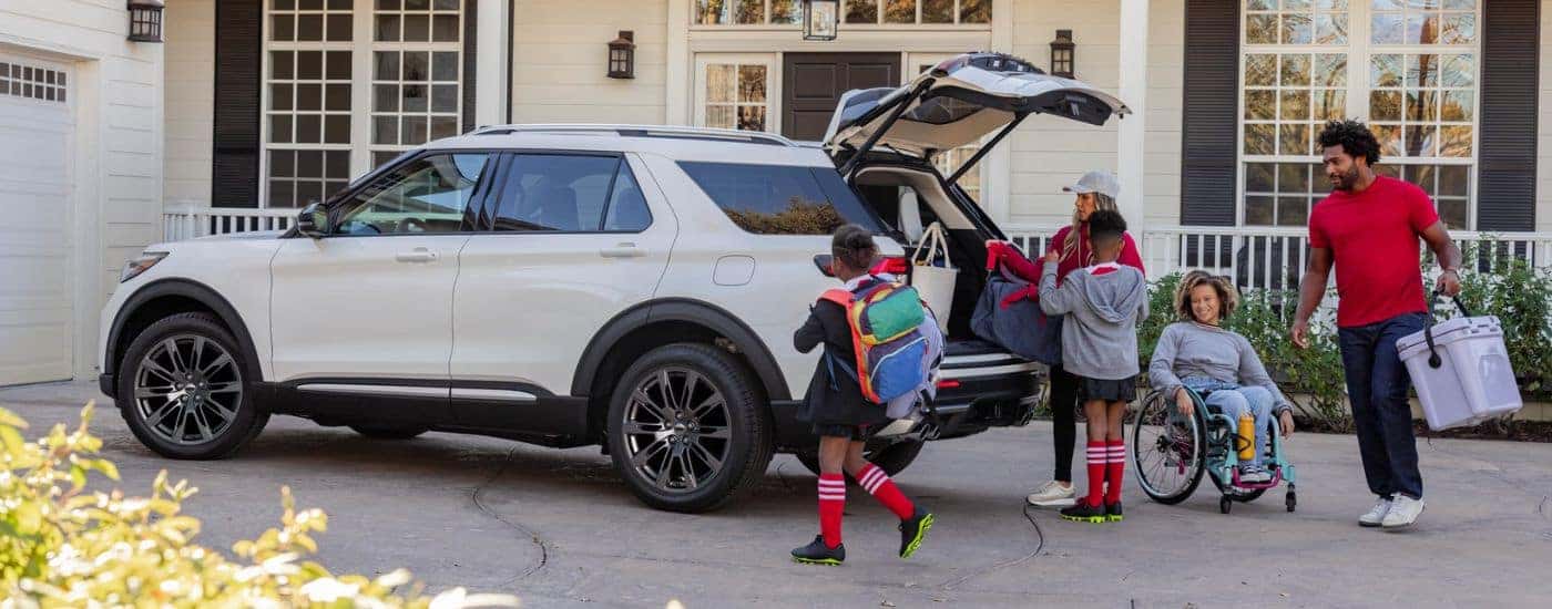 White 2026 Ford Explorer with a family loading luggage into the cargo area