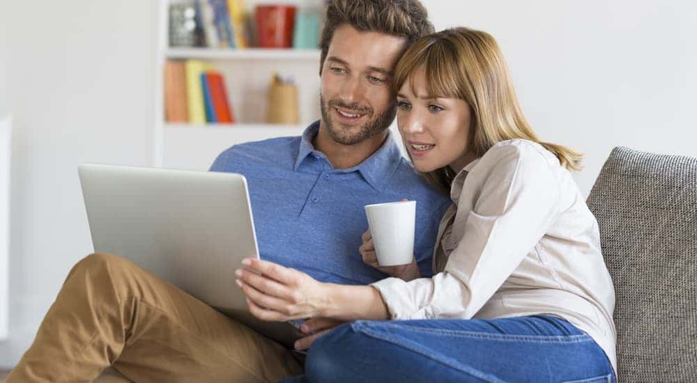 Couple looking up the vehicle history report on a laptop
