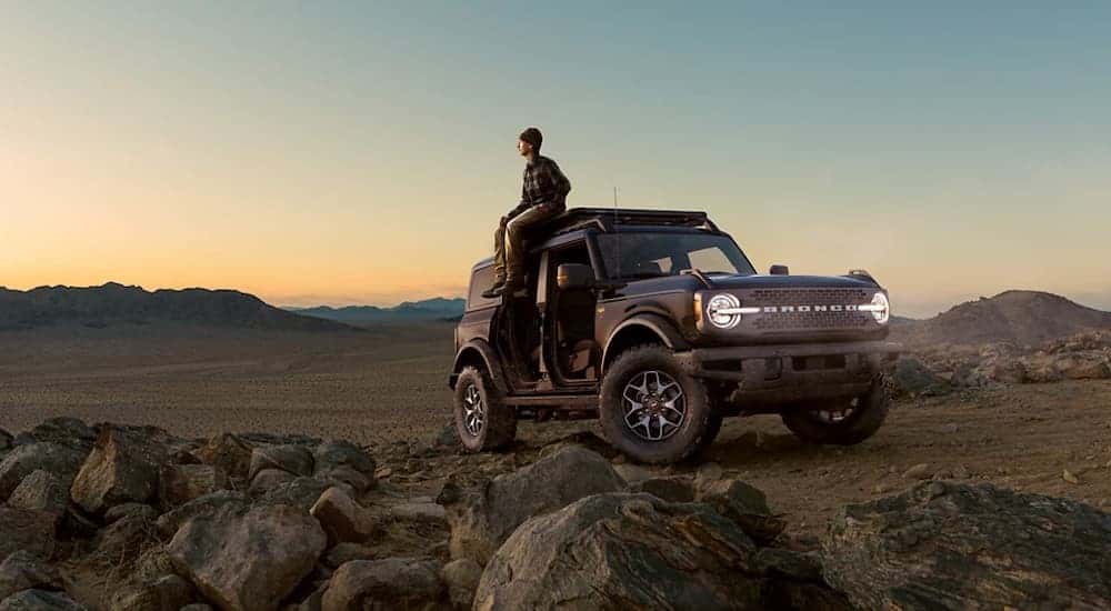 Black 2021 Ford Bronco in the Badlands with a a man sitting on the roof.