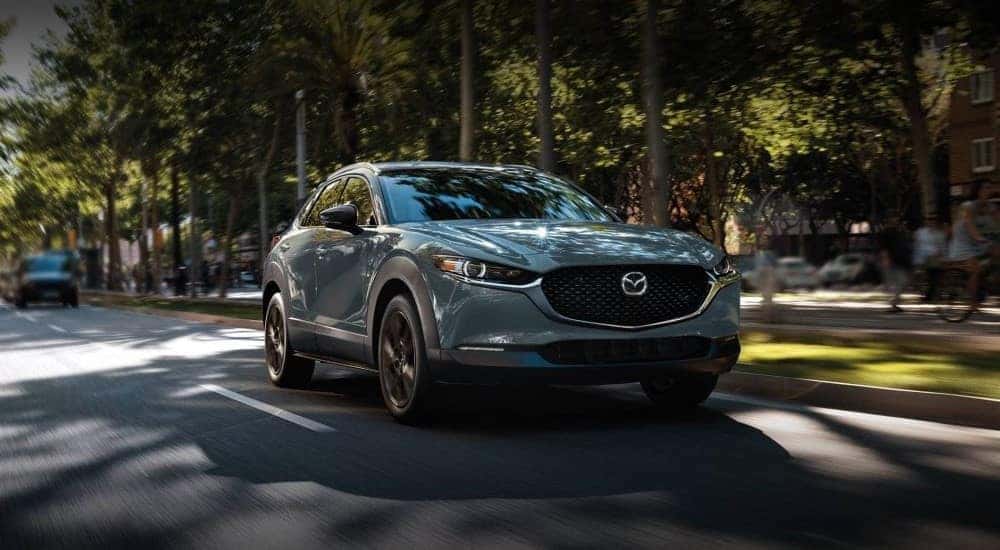 Grey 2023 Mazda CX-30 driving on a tree lined road