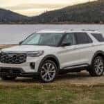 A white 2025 Ford Explorer Platinum is shown parked by a lake.