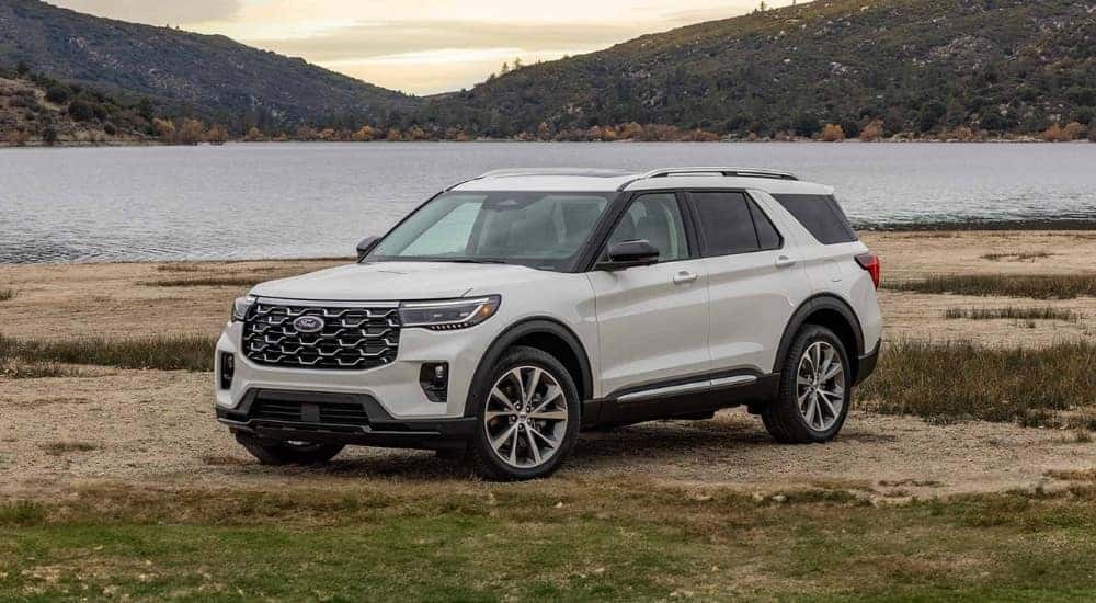 A white 2025 Ford Explorer Platinum is shown parked by a lake.
