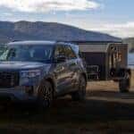 A blue 2026 Ford Explorer parked in front of a lake with a trailer attached.